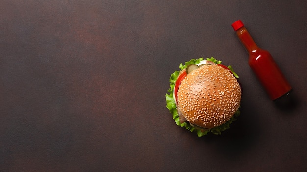 Zelfgemaakte hamburger met ingrediënten rundvlees, tomaten, sla, kaas, ui, komkommers en frietjes op roestige achtergrond. Bovenaanzicht.