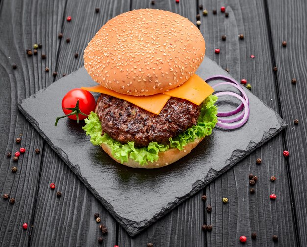 Zelfgemaakte hamburger met salade en kaas op zwarte lei