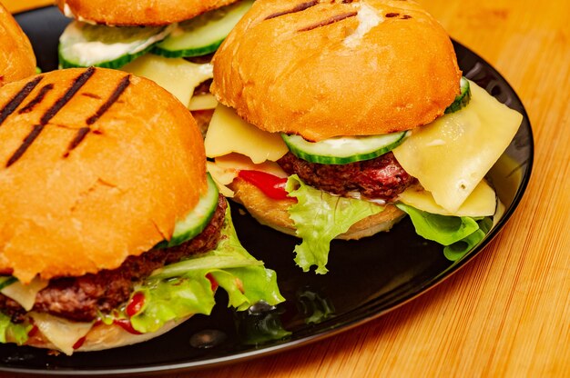 Zelfgemaakte hamburgers op houten achtergrond. Rundvleesburgers, sla, saus, hamburgerbroodje op een bord.