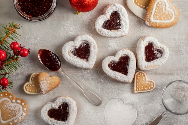 Foto zelfgemaakte hartvormige koekjes met frambozenjam op witte houten tafel voor kerstmis of valentijnsdag. bovenaanzicht