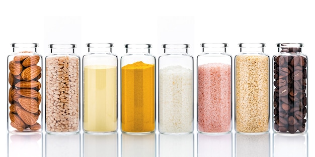 Zelfgemaakte huidverzorging met natuurlijke ingrediënten en kruiden in glazen flessen isoleren op wit.