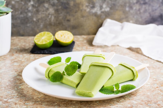 Zelfgemaakte ijslolly gemaakt van avocado, kokosmelk en limoen op een bord op tafel