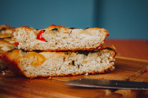 Foto zelfgemaakte italiaanse focaccia, met tomaat en olijfolie op een rustieke houten achtergrond.