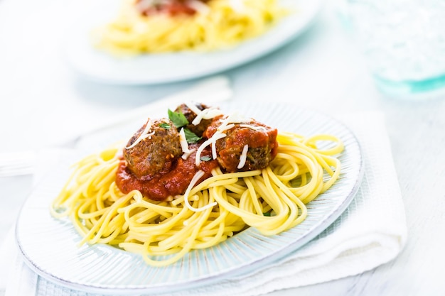 Zelfgemaakte Italiaanse gehaktballen gegarneerd met koriander en Parmezaanse kaas over spaghetti voor het diner.