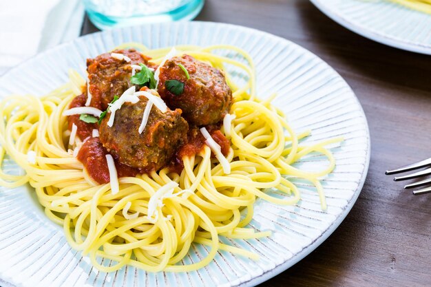 Zelfgemaakte Italiaanse gehaktballen gegarneerd met koriander en Parmezaanse kaas over spaghetti voor het diner.