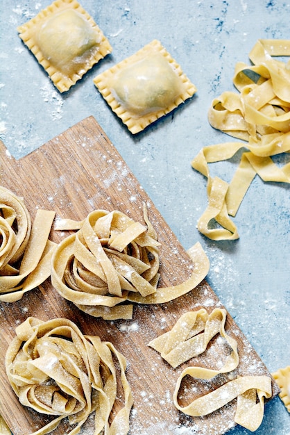 Zelfgemaakte Italiaanse pasta, ravioli, fettuccine, tagliatelle op een houten bord