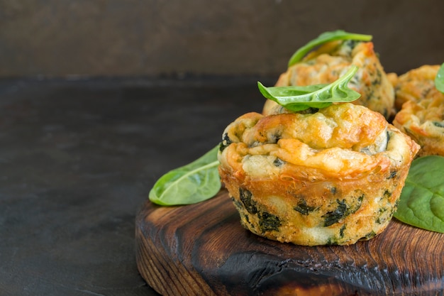 Zelfgemaakte kaasmuffins met spinazie. op een donkere achtergrond.