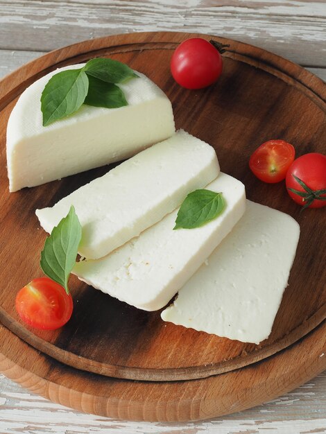 Zelfgemaakte kaasplakken op een ronde snijplank met tomaten en basilicumblaadjes