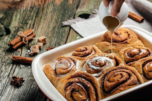 Zelfgemaakte kaneelbroodjes. Kaneelbroodjes met roomsaus op houten ondergrond. bovenaanzicht.