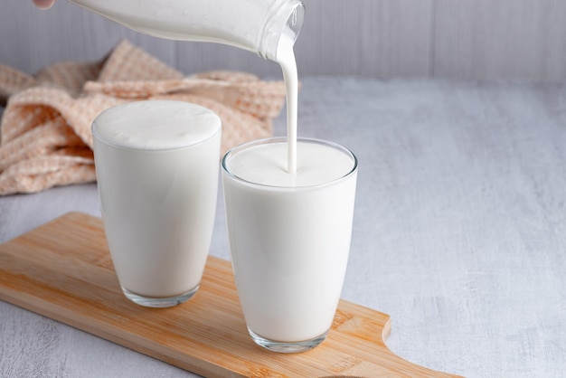 Zelfgemaakte kefir karnemelk of yoghurt met probiotica gieten Yoghurt vloeit uit een glazen fles