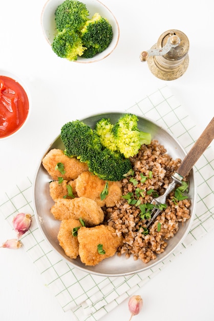 Zelfgemaakte kipnuggets met boekweit en groenten op een bord