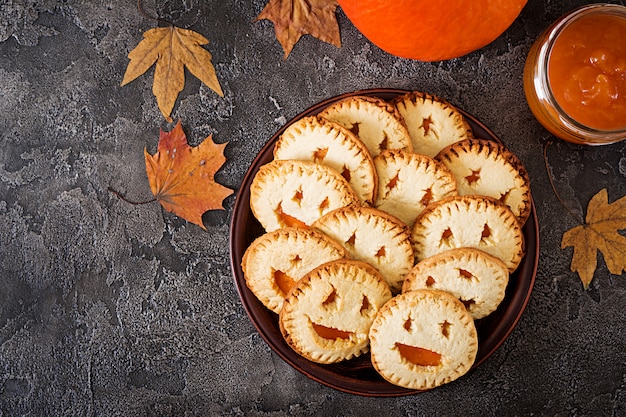 Zelfgemaakte koekjes in de vorm als Halloween-hefboom-o-lantaarnpompoenen op de donkere lijst. Bovenaanzicht