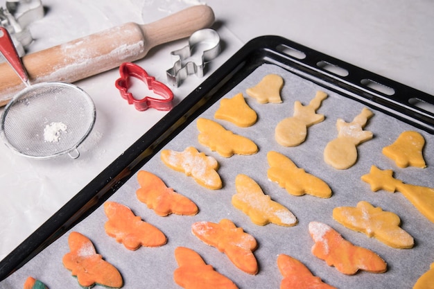 Zelfgemaakte koekjes in de vorm van vlinders, bellen en sneeuwmannen voor het bakken op een bakplaat