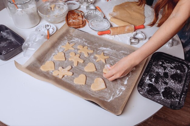 Zelfgemaakte koekjes maken. De laatste fase van het koken. De huisvrouw verdeelt de koekjes op bakpapier voordat ze in de oven gaan. Zoete en heerlijke koekjes.