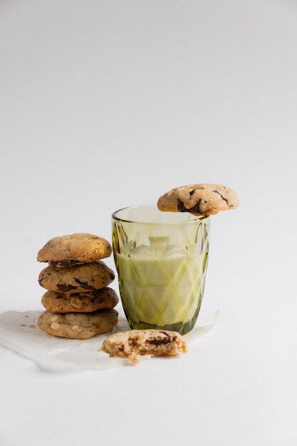 Zelfgemaakte koekjes met stukjes chocolade naast een glas melk op een witte achtergrond