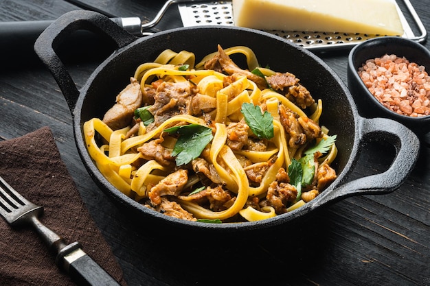 Zelfgemaakte konijnenstoofpot pappardelle set, in gietijzeren pan of pan, op zwarte houten tafel