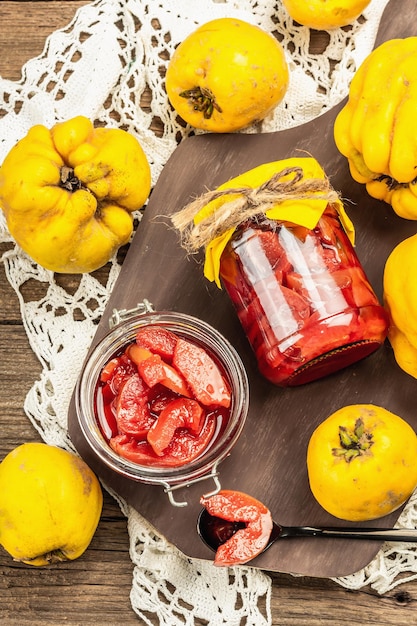 Zelfgemaakte kweeperenjam in een glazen pot. Vers fruit, zoete marmelade, vintage arrangement. Oude houten achtergrond, bovenaanzicht