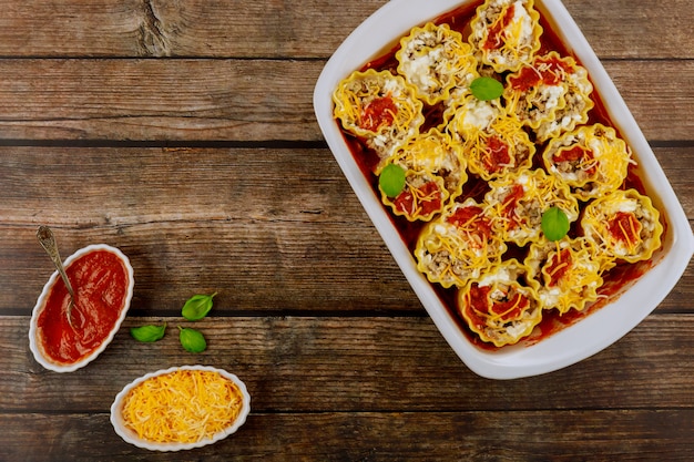 Zelfgemaakte lasagnebroodjes in een ovenschaal op hout. Bovenaanzicht.