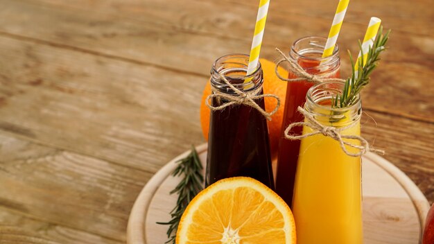 Zelfgemaakte limonade in flesjes. veelkleurige sappen en fruit op houten achtergrond