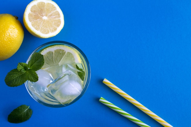 Zelfgemaakte limonade met citroen en munt in het glas op de blauwe tafel. Bovenaanzicht.