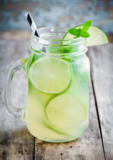 Zelfgemaakte limonade met limoenmunt in een glazen pot op een rustieke houten tafel