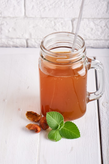 Zelfgemaakte limonade van gedroogde vruchten in een pot op een lichte tafel.