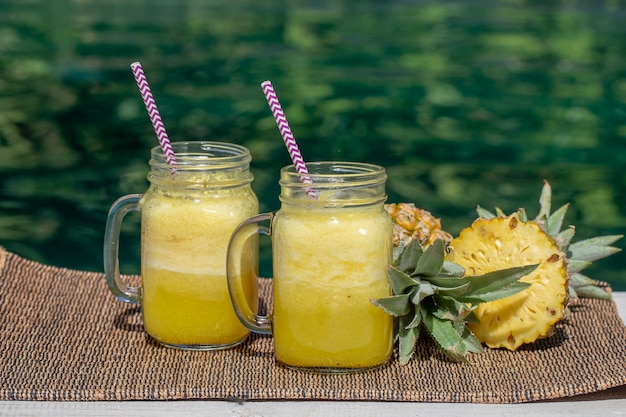 Zelfgemaakte mango- en ananassmoothie gemaakt met kokosmelk in twee glazen mok bij het zwembad Eiland Bali Indonesië Verfrissende tropische fruitdrank