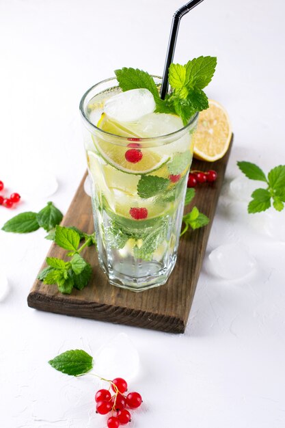 Zelfgemaakte mojito cocktail met citroen, limoen, muntblaadjes, ijs en rode bes. Zomer drankje concept.