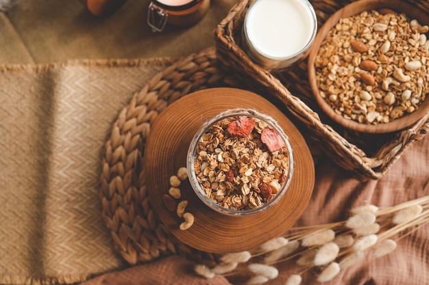 Zelfgemaakte muesli in een glazen pot tegen de achtergrond van melkkaars en decor goedemorgen concept