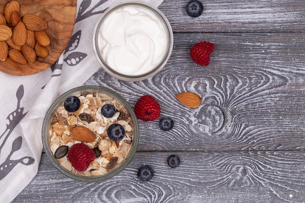 Zelfgemaakte muesli met noten, frambozen en bosbessenyoghurt op een grijs witgekalkt rustiek tafelblad