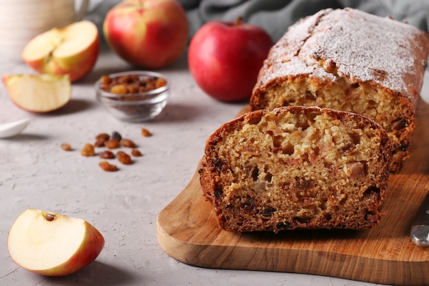 Zelfgemaakte muffin met appels en rozijnen op een houten bord op een grijze achtergrond, close-up, kopie ruimte