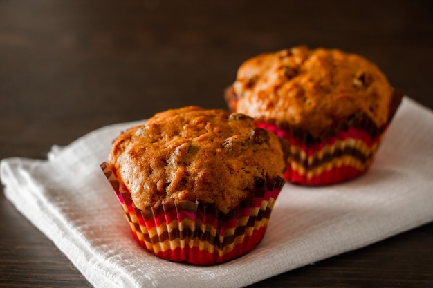 Zelfgemaakte muffins met rozijnen op een houten ondergrond Cupcake in een papieren mal op een wit servet