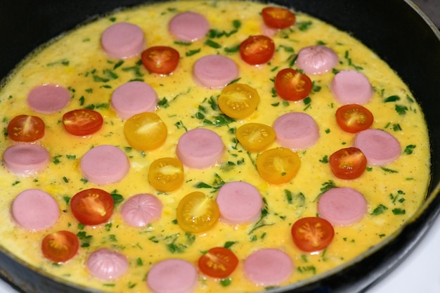 Foto zelfgemaakte omelet met worsttomaten en kruidenclose-up