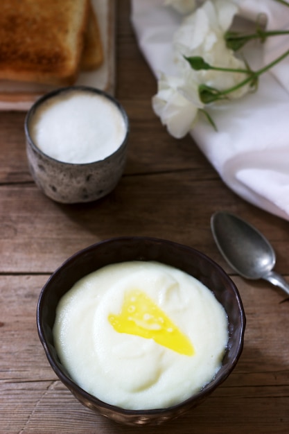 Zelfgemaakte ontbijt van griesmeel pap, koffie met melk en toast op een houten oppervlak. Rustieke stijl.