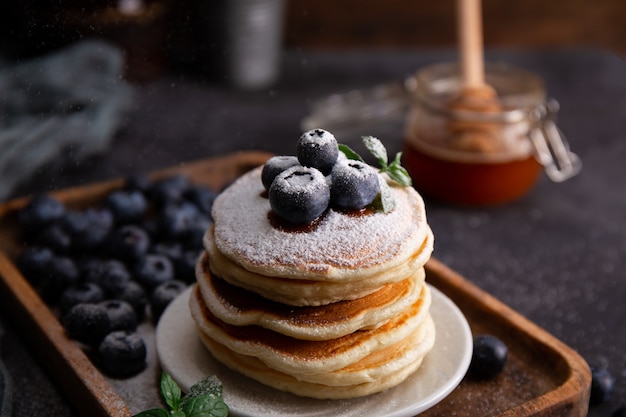 Zelfgemaakte pannenkoeken met bosbessen en poedersuiker op tafel close-up.