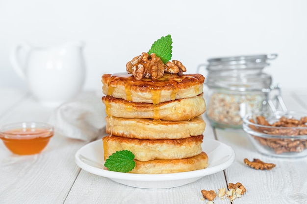 Zelfgemaakte pannenkoeken met honing, noten en munt op een witte achtergrond. Detailopname.