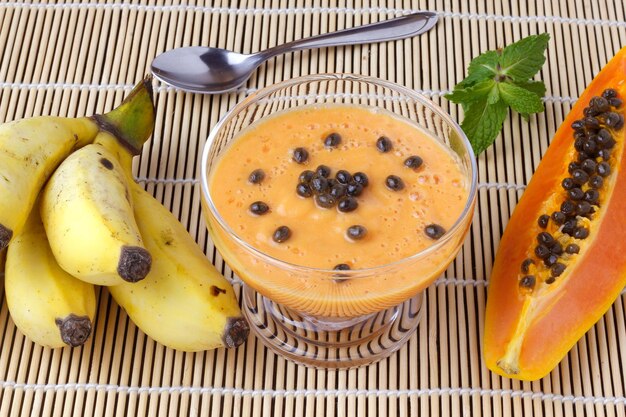 Zelfgemaakte papaya smoothie met tropisch fruit en munt in glazen kom over rustieke houten tafel. bovenaanzicht