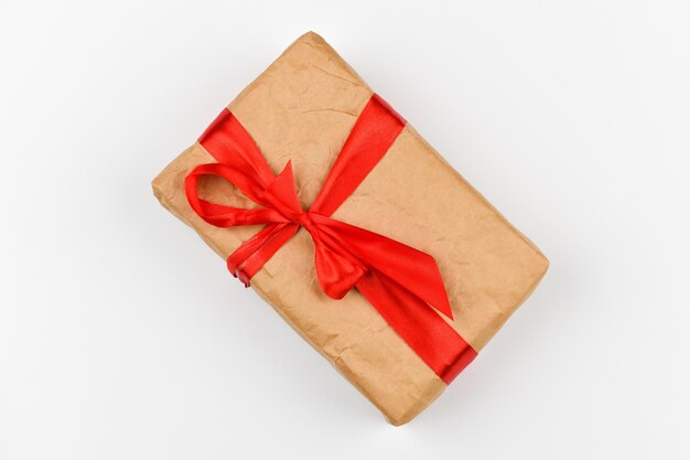 Foto zelfgemaakte papieren geschenkverpakking met een rode strik op een witte achtergrond