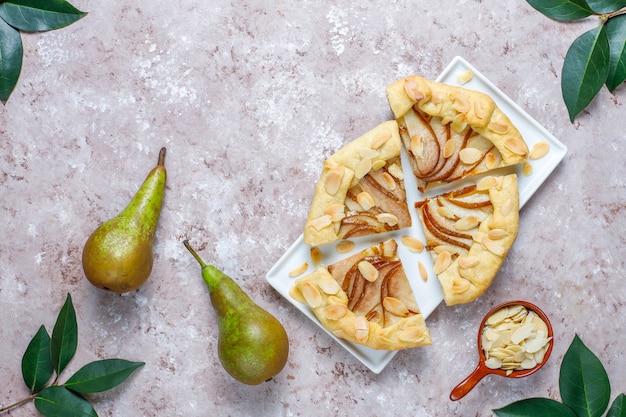 Zelfgemaakte peer galette taart met amandel bladeren en verse rijpe groene peren