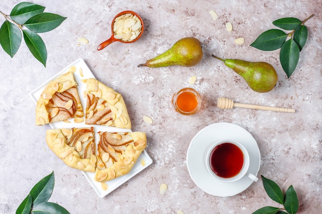 Zelfgemaakte peer galette taart met amandel bladeren en verse rijpe groene peren