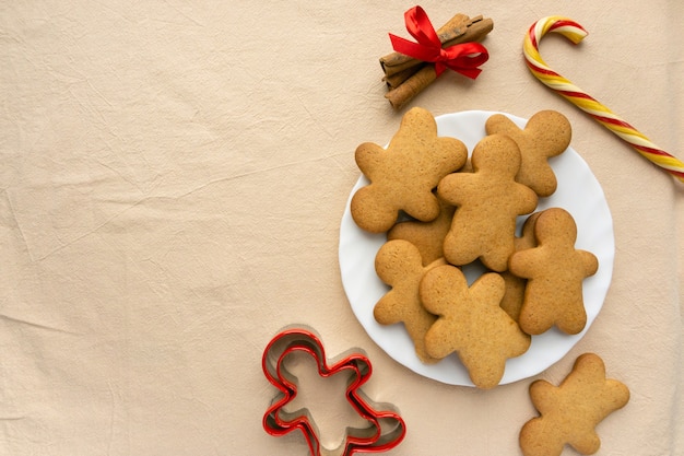 Foto zelfgemaakte peperkoek kerstkoekjes in de vorm van een man op beige textiel achtergrond, copyspace.