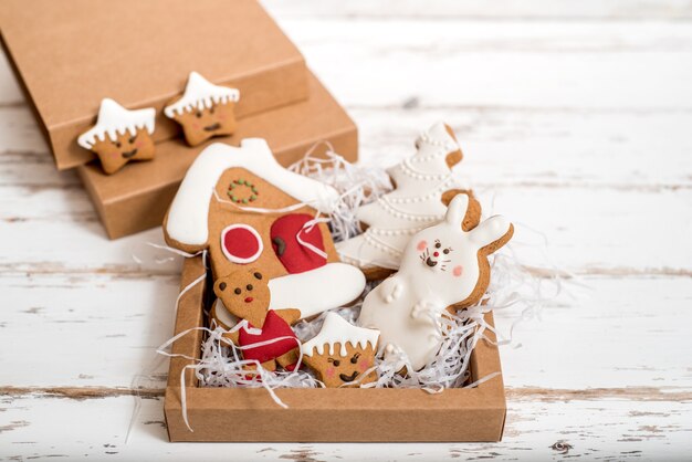 Zelfgemaakte peperkoek kerstkoekjes op houten tafel. Nieuwjaarscadeau in een doos, witte verrassing