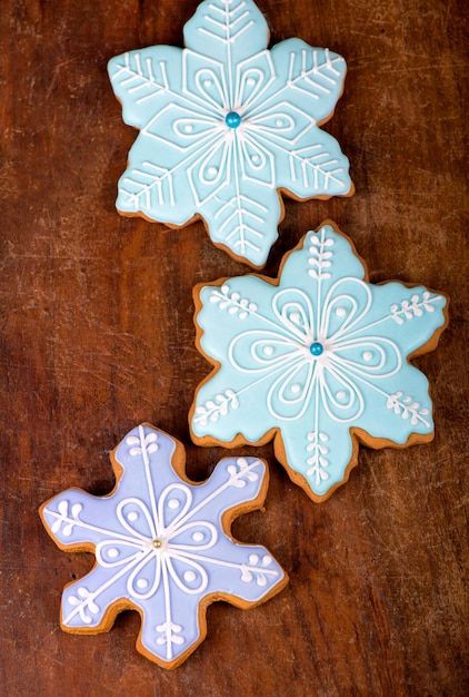 Zelfgemaakte peperkoekkoekjes, feestelijke kerst- en nieuwjaarssnoepjes in de vorm van een blauwe sneeuwvlokkenachtergrondkaart, op een houten bord