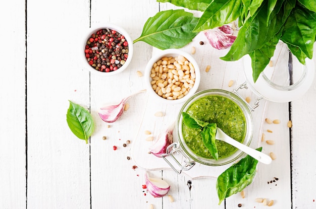 Zelfgemaakte pesto saus verse basilicum, pijnboompitten en knoflook op witte houten achtergrond.