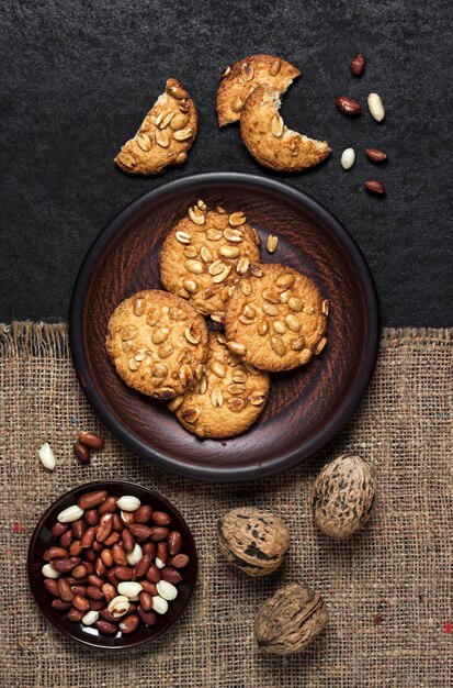 Zelfgemaakte pinda cookies op een bruine plaat met rauwe pinda's