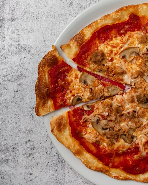 Zelfgemaakte pizza met tomaten kaas champignons tonijn groenten ham en verse kruiden met kopieerruimte