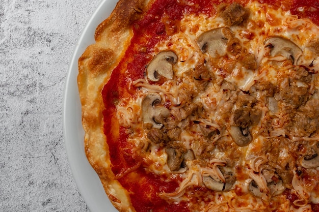 Zelfgemaakte pizza met tomaten kaas champignons tonijn groenten ham en verse kruiden met kopieerruimte