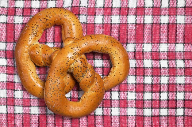 Zelfgemaakte pretzels met maanzaad op rood tafelkleed, bovenaanzicht