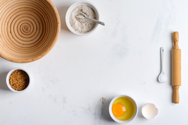 Zelfgemaakte productie van vers gezond brood van andere gebak uit natuurlijke ingrediënten op een lichtgrijze tafel.