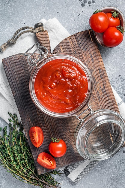 Zelfgemaakte rode tomatensaus met basilicum in glazen pot Grijze achtergrond Bovenaanzicht